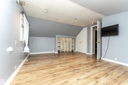 Wood-finish flooring, built-in shelving, track lighting, and a wall-mounted display - 