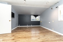 Wood-finish flooring with white trim, track lighting, and a white interior door - 