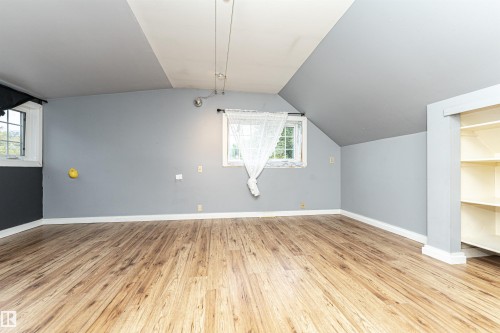 Wood-finish flooring, multiple windows, built-in shelving, and a sloped ceiling - 10930 80 Avenue Nw, Edmonton, AB 