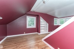 Wood-finish flooring, multiple windows, built-in shelving, and a sloped ceiling - 