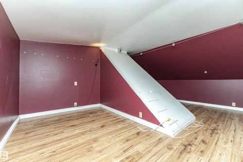 Sloped ceiling, wood-finish flooring, track lighting, and a built-in access panel - 10930 80 Avenue Nw, Edmonton, AB 