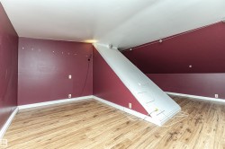 Sloped ceiling, wood-finish flooring, track lighting, and a built-in access panel - 
