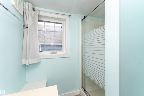 Window with grid pattern and white trim, alongside a shower enclosure with frosted glass - 10930 80 Avenue Nw, Edmonton, AB 