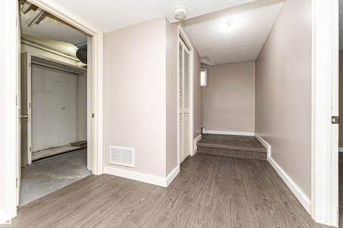 Wood-finish flooring with white trim, interior door, a louvered bi-fold closet door, and a built-in step - 10930 80 Avenue Nw, Edmonton, AB 
