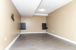 Room featuring wood-finish flooring, recessed lighting, and wall-mounted shelving units - 