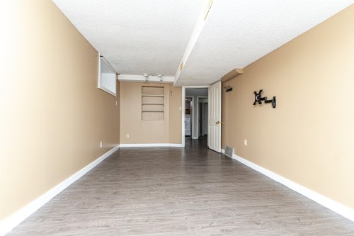 Spacious room featuring wood-finish flooring, neutral-toned walls, and recessed shelving - 10930 80 Avenue Nw, Edmonton, AB 