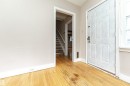 Wood-finish flooring throughout, with a paneled entry door and a visible staircase - 10930 80 Avenue Nw, Edmonton, AB 