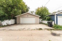Detached garage with horizontal siding, a white overhead door, and a concrete driveway - 