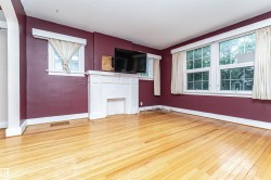 Hardwood flooring, white trim, multiple windows, decorative fireplace, and an architectural archway - 
