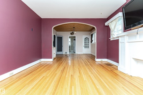 Hardwood flooring, arched doorway, built-in fireplace surround, built-in cabinetry, and white trim - 10930 80 Avenue Nw, Edmonton, AB 