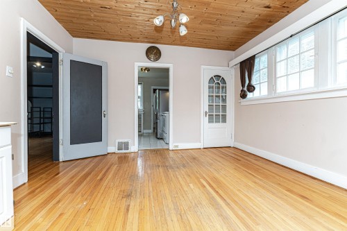 Wood-finish flooring, wood-paneled ceiling, multiple windows, interior doors with transom-style glass, and a ceiling-mounted light fixture - 10930 80 Avenue Nw, Edmonton, AB 