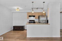 Kitchen featuring stainless steel appliances, light wood cabinetry, and a countertop bar - 