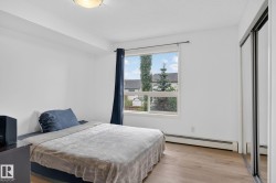 Bright bedroom featuring a large window, light wood-finish flooring, and white walls - 