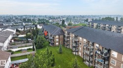 Multi-story residential buildings with private balconies, set amidst expansive green spaces - 