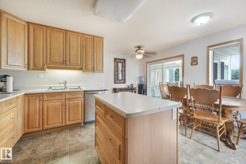 Kitchen featuring wood cabinetry, white countertops, tile flooring, a stainless steel dishwasher, and a center island with storage - 54 Buskmose Dr, Rural Wetaskiwin County, AB - Indoor Photo Showing Kitchen With Double Sink