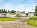 Spacious property featuring a light-toned exterior with a green metal roof, a fenced perimeter, a gravel driveway, and an additional detached two-stall garage - 54 Buskmose Dr, Rural Wetaskiwin County, AB  - Outdoor 