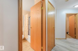 Hallway featuring wood-finish doors, light wood-finish flooring, and a ceiling-mounted light fixture - 
