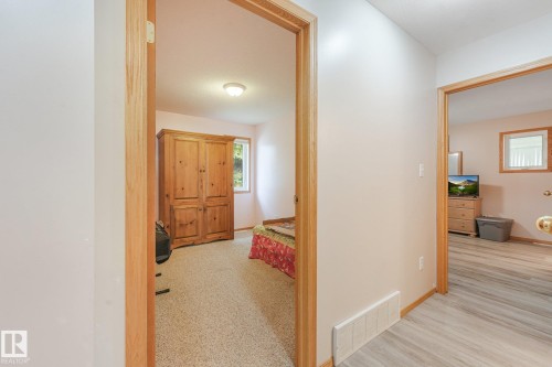 Hallway featuring light-toned wood-finish flooring and two doorways with natural wood trim - 54 Buskmose Dr, Rural Wetaskiwin County, AB - Indoor