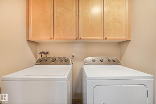 Laundry area featuring overhead wood cabinetry and a washer and dryer set - 54 Buskmose Dr, Rural Wetaskiwin County, AB - Indoor Photo Showing Laundry Room