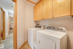 Dedicated laundry area featuring upper wood cabinetry and a tiled floor - 