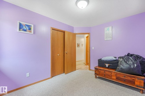Room featuring light purple wall paint, wood-finish flooring in the hallway, and a built-in ceiling light fixture - 54 Buskmose Dr, Rural Wetaskiwin County, AB - Indoor Photo Showing Bedroom