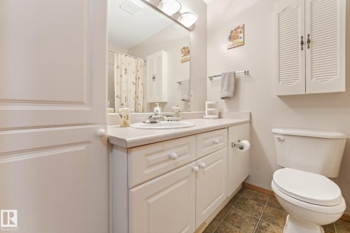 Bathroom featuring a white vanity with integrated sink, a large wall-mounted mirror, a built-in toilet, and tile flooring - 54 Buskmose Dr, Rural Wetaskiwin County, AB - Indoor Photo Showing Bathroom