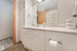 Bathroom vanity featuring a single basin, ample countertop space, integrated mirror, and built-in white cabinetry with beadboard accents - 