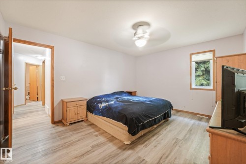 Spacious room featuring wood-finish flooring, a contemporary ceiling light fixture, and a window with a roller shade - 54 Buskmose Dr, Rural Wetaskiwin County, AB - Indoor Photo Showing Bedroom