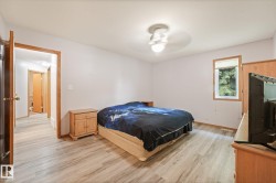 Spacious room featuring wood-finish flooring, a contemporary ceiling light fixture, and a window with a roller shade - 