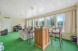 Sunroom with extensive window line, green turf flooring, white paneled ceiling, and light-colored siding walls - 