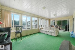 Sunroom featuring expansive windows, green carpeting, horizontal wall paneling, and a white paneled ceiling with flush-mount lighting fixtures - 