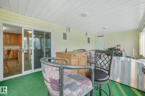 Enclosed patio featuring light-toned vinyl siding, a white tongue-and-groove ceiling, and green artificial turf flooring - 54 Buskmose Dr, Rural Wetaskiwin County, AB - Outdoor With Deck Patio Veranda With Exterior
