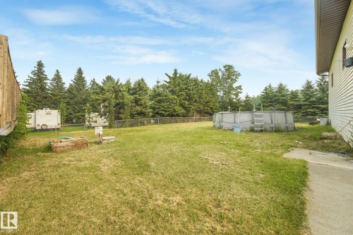 Fenced backyard featuring an above-ground pool and mature evergreen trees - 54 Buskmose Dr, Rural Wetaskiwin County, AB - Outdoor