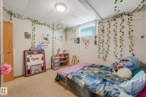 Carpeted room featuring a white ceiling, a window, and a wooden door - 54 Buskmose Dr, Rural Wetaskiwin County, AB - Indoor Photo Showing Bedroom