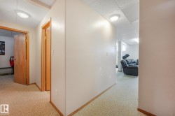 Hallway featuring wood-finish door frames, wood-finish baseboards, and a textured drop ceiling - 