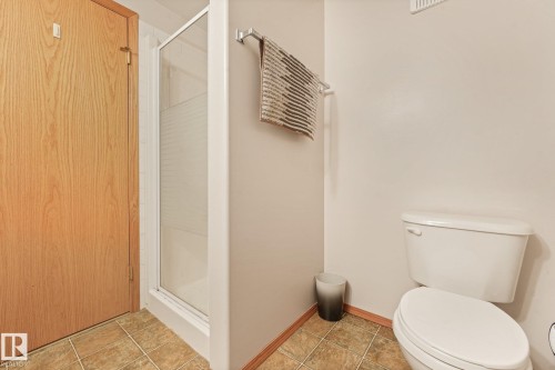 Bathroom featuring tile flooring, a glass-enclosed shower, and a white toilet - 54 Buskmose Dr, Rural Wetaskiwin County, AB - Indoor Photo Showing Bathroom