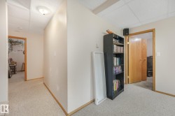 Carpeted hallway featuring wood-finish trim and solid core doors - 