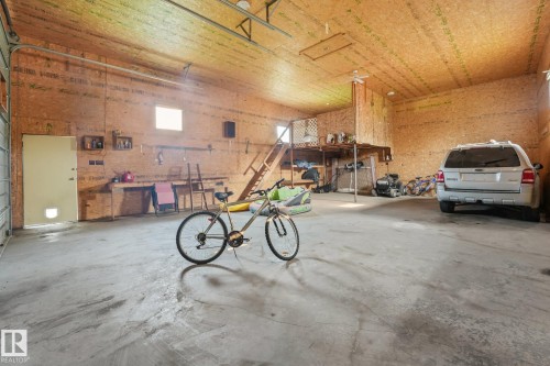 Spacious garage featuring concrete flooring and exposed wood-panel walls - 54 Buskmose Dr, Rural Wetaskiwin County, AB - Indoor Photo Showing Garage