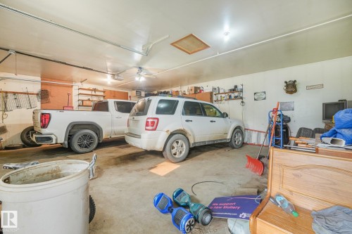 Spacious two-vehicle garage featuring a concrete floor, built-in shelving, and overhead lighting - 54 Buskmose Dr, Rural Wetaskiwin County, AB - Indoor Photo Showing Garage