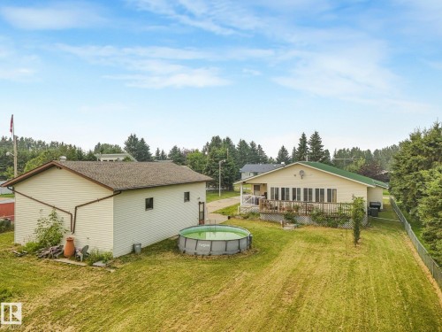 Expansive backyard featuring a large accessory building, above-ground pool, and a chain-link fence - 54 Buskmose Dr, Rural Wetaskiwin County, AB - Outdoor With Exterior