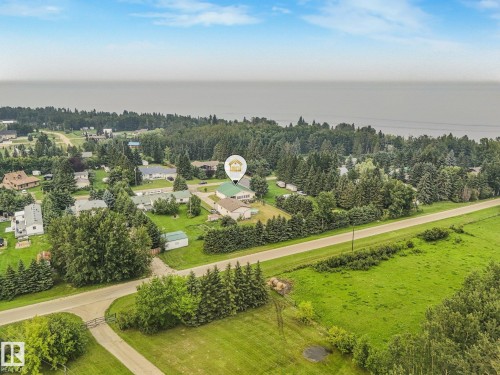 Expansive property featuring a green-roofed structure, mature trees, and a paved roadway - 54 Buskmose Dr, Rural Wetaskiwin County, AB - Outdoor With View