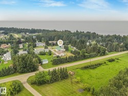 Expansive property featuring a green-roofed structure, mature trees, and a paved roadway - 