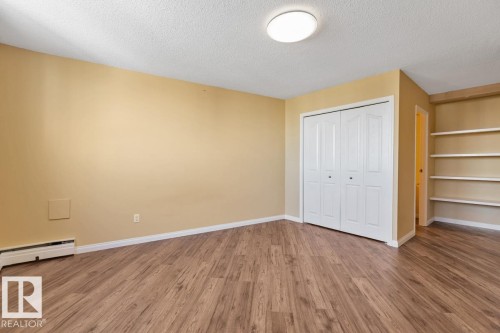 Wood-finish flooring, built-in shelving, white bi-fold closet, and ceiling-mounted flush light fixture - #1307 10045 117 St Nw, Edmonton, AB 