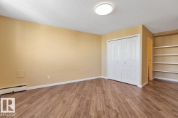 Wood-finish flooring, built-in shelving, white bi-fold closet, and ceiling-mounted flush light fixture - 
