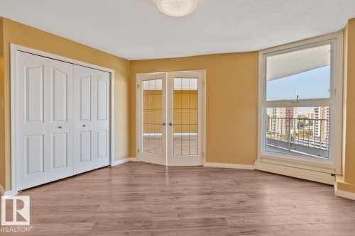 Wood-finish flooring, white bi-fold closet doors, French doors with glass panels, large window, and light fixture - #1307 10045 117 St Nw, Edmonton, AB 