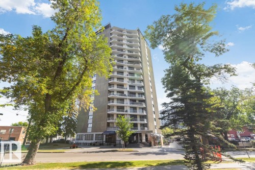 High-rise building with a grey facade, multiple tiers of white balconies, and a prominent ground-level entrance - #1307 10045 117 St Nw, Edmonton, AB 