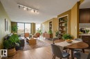 Expansive windows, wood-finish flooring, recessed built-in shelving, track lighting, and a partial kitchen with a subway tile backsplash - #1307 10045 117 St Nw, Edmonton, AB 