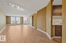 Expansive main living area with wood-finish flooring, track lighting, and a built-in shelving unit - #1307 10045 117 St Nw, Edmonton, AB 