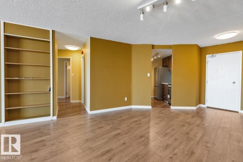 Wood-finish flooring throughout, built-in shelving unit, and track lighting - #1307 10045 117 St Nw, Edmonton, AB 