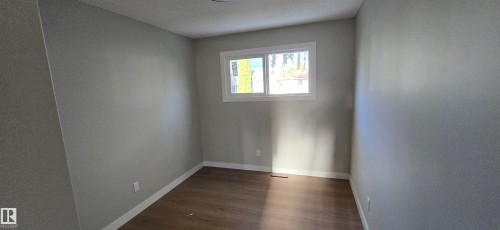 Neutral tone walls featuring wood-finish flooring and a white-framed window - 13812 63 Street Nw, Edmonton, AB 